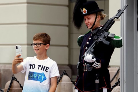 Child takes selfie with security guard in uniform in front of the Royal Palace in Oslo, Oslo,
