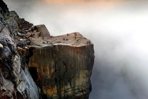 A lonely rock edge emerges from the clouds as the sun illuminates the horizon, Preikestolen,