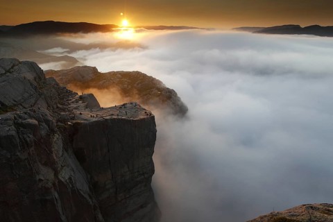 The rising sun paints dramatic colors over the sea of clouds at Preikestolen, Preikestolen,