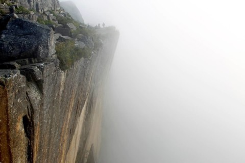 A rocky edge covered in fog rises majestically on the way to Preikestolen, Preikestolen, Rogaland,