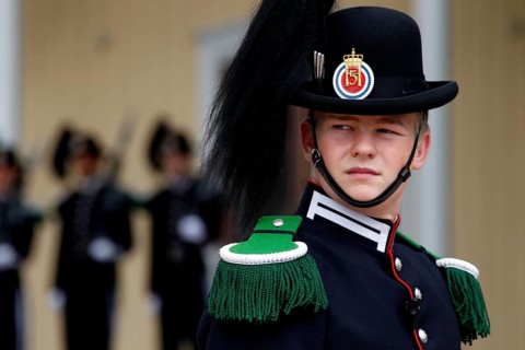Norwegian security guard in decorative uniform wearing a hat decorated with feathers in front of