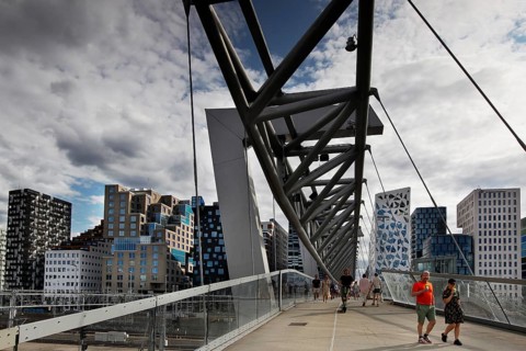 Modern footbridge in Oslo between new buildings, lively with people in cloudy sky, Oslo, Bydel