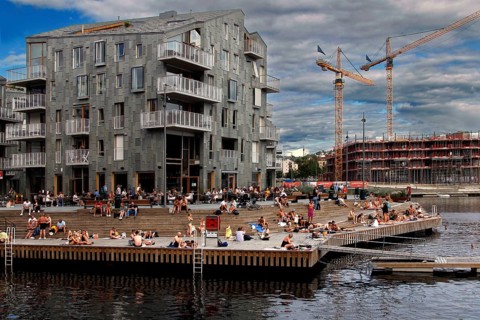 People enjoy summer on the shore next to modern buildings, Oslo, Norway