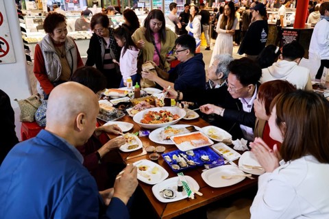 People eat at a table at the lively Sydney fish market, Sydney, New South Wales, Australia