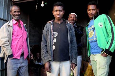 Group of men posing in front of a small shop and smiling at the camera, Awaday, Afar, Ethiopia
