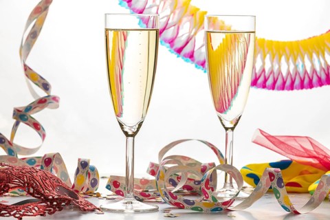 Two champagne glasses filled with colorful streamers, carnival