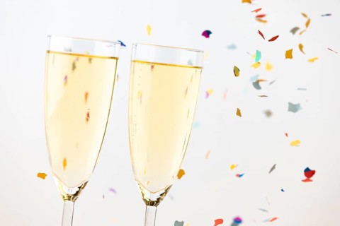 Two champagne glasses with colorful confetti in the background