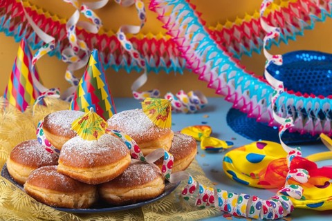 A plate of donuts surrounded by colorful party hats, streamers and garlands, carnival