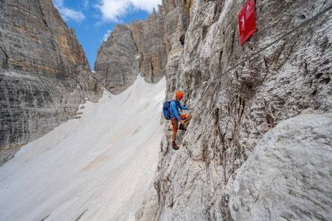 Mountaineer climbs on a steep rock face in the Via Ferrata Brentari via ferrata, spectacular