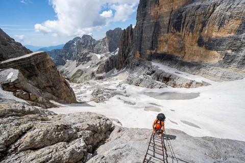 Mountaineer climbs on a ladder in the Via Ferrata Brentari via ferrata, spectacular mountain