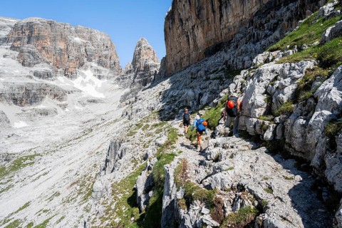 Three mountaineers on a hiking trail to Sella della Tosa, mountainous landscape in the Brenta