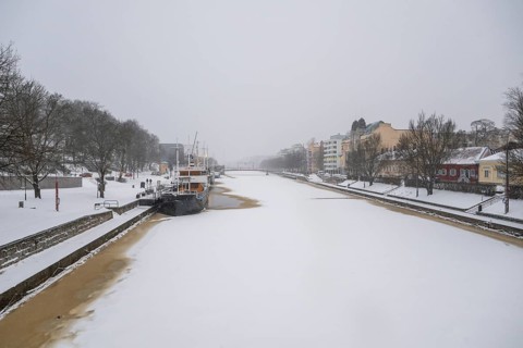 Ships moored on the banks of the frozen Aurajoki River, wintery Turku or Swedish Åbo,