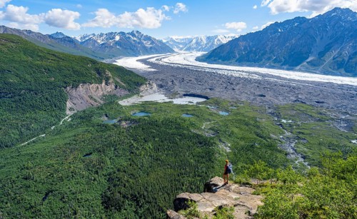 Young woman on a rocky outcrop enjoying the view, view of impressive mountain landscape with