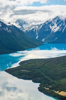 View of snowy mountains in spring and turquoise Kenai Lake with reflection, Slaughter Ridge Trail,
