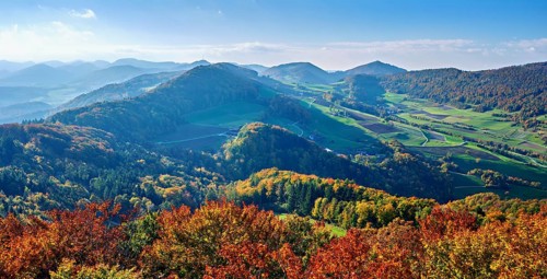 View of an autumnal forest from the Gisliflue, behind the Jura foothills with Wasserfluh and