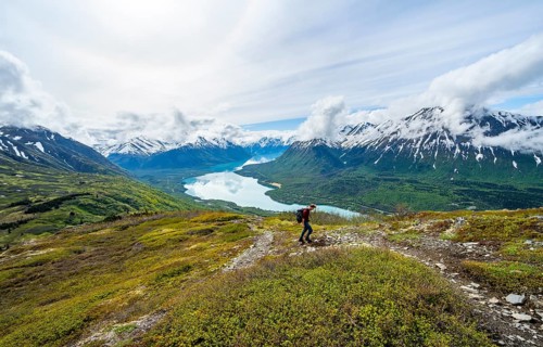 Climbers on a hiking trail, Slaughter Ridge Trail, view of snowy mountains and turquoise lake Kenai