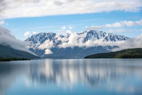 Snowy mountains in spring are reflected in turquoise blue Kenai Lake, Cooper Landing, Kenai
