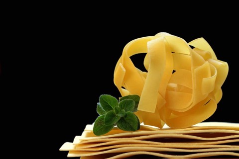 Uncooked lasagna leaves and fettuccine, noodle nest
