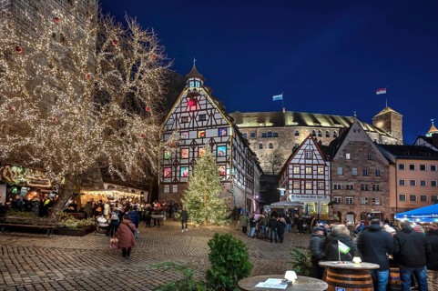 Christmassy illuminated square with the historic Pilate House with advent calendar, in the evening