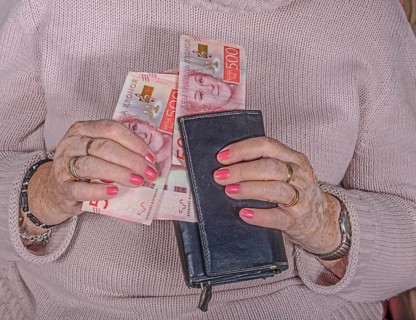 An elderly woman's hands take out Swedish banknotes from a wallet