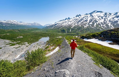 Hikers on glacial moraine, view of the vast Tsina River valley with mountains, Worthington Glacier