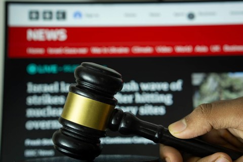 Dhaka, Bangladesh- 20 June 2025: A hand holds a gavel in front of a computer screen displaying