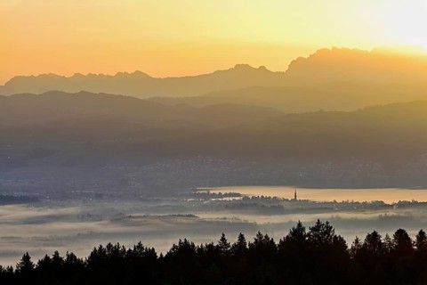 View from Horben of Lake Zug with the city of Cham and Zug covered in fog, behind it the