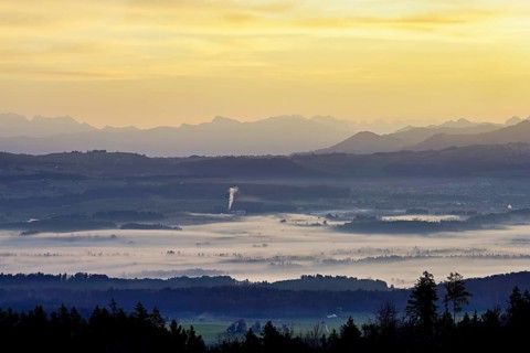 View from Horben of the Reuss Valley covered in fog, behind it the Glarus Alps in the light of the