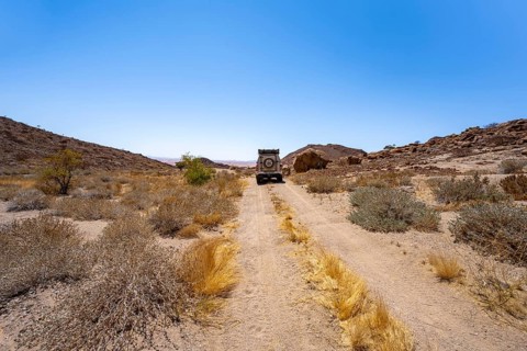 Toyota Hilux off-road vehicle on a sandy track, desert landscape with Brandberg, Erongo,
