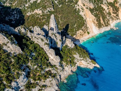 Picturesque rocky coast, cliffs with L'Aguglia pinnacle, blue sea and Cala Goloritzé beach, aerial