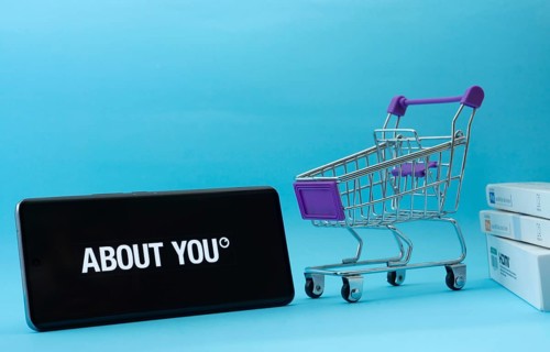 Dhaka, Bangladesh- 21 Nov 2025: Smartphone with About You logo next to a small shopping cart and