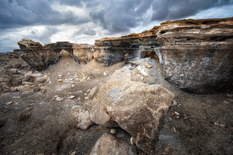 Eroded rock formations in volcanic landscape with dramatic cloudy skies, Ciudad Estratificada or