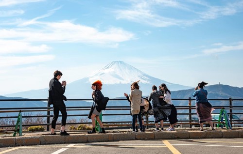 Tourists enjoy the view and take pictures, view of the snow-covered summit of Mount Fuji volcano in