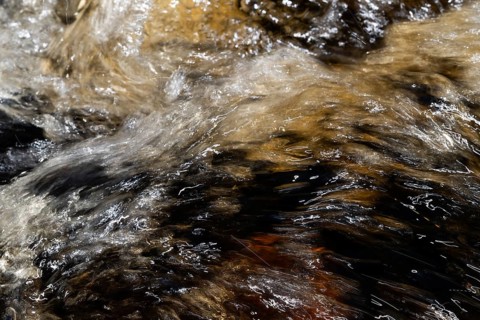 Stream flow with dark water, reflections and turbulences, long exposure, Sweden
