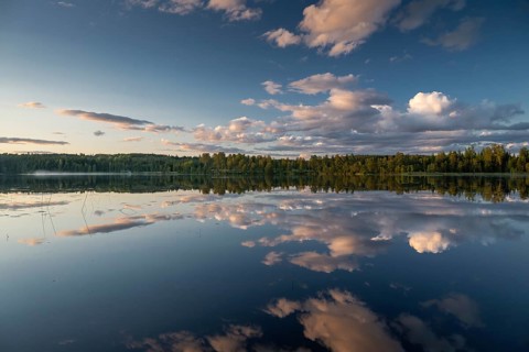 Clouds reflected on the water surface, forest lake, evening mood, at Sunne, Sweden