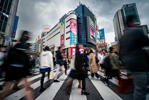 Crowd crossing zebra crossing on a large intersection, motion blur, back modern houses with