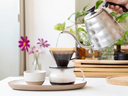 Barista preparing filter coffee using a modern kettle and a ceramic dripper