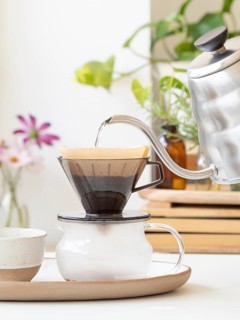 Hot water being poured from a modern kettle into a coffee filter, brewing a fresh cup of coffee