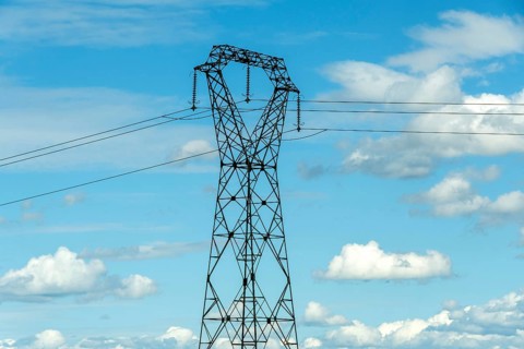 High voltage power lines against a bright blue sky with scattered clouds, Puy de Dome, Auvergne