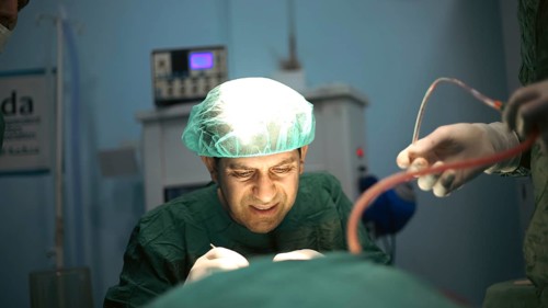 Several doctors performing a complex surgical operation inside an operating room for a displaced