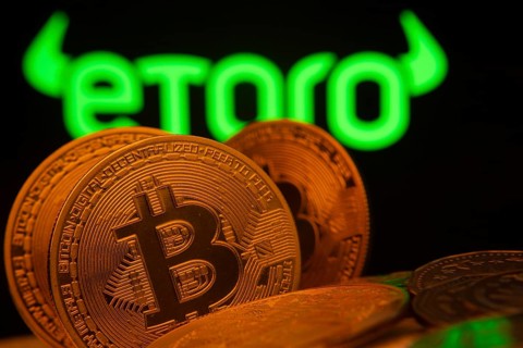 Dhaka, Bangladesh- 27 March 2025: Close-up of Bitcoin coins with the eToro logo visible on a screen