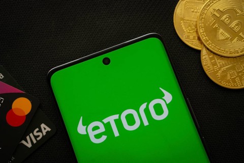 Dhaka, Bangladesh- 15 July 2025: Smartphone displaying eToro logo surrounded by Bitcoin coins and