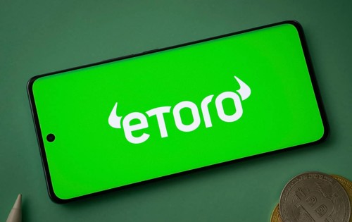 Dhaka, bangladesh- 12 June 2025: eToro logo displayed on a smartphone with Bitcoin coins on a green