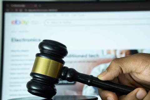 Dhaka, Bangladesh- 20 June 2025: A hand holds a gavel in front of a computer screen displaying