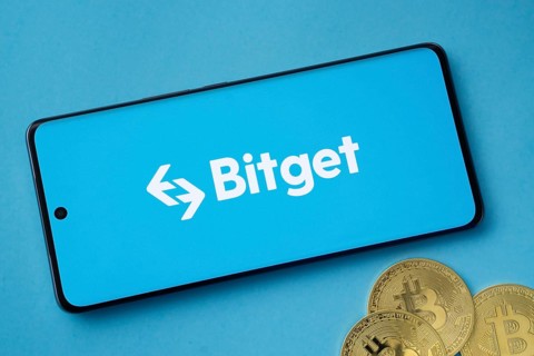 Dhaka, Bangladesh- 27 July 2025: Bitget logo displayed on a smartphone with Bitcoin coins on a blue