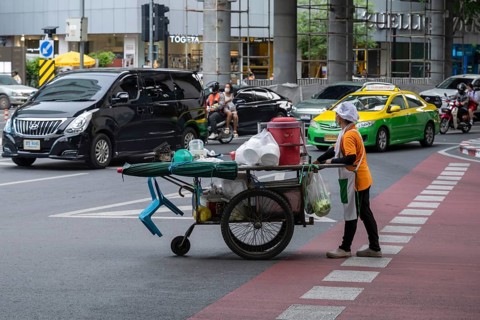 Street crossing woman with cookshop, Bangkok, Thailand