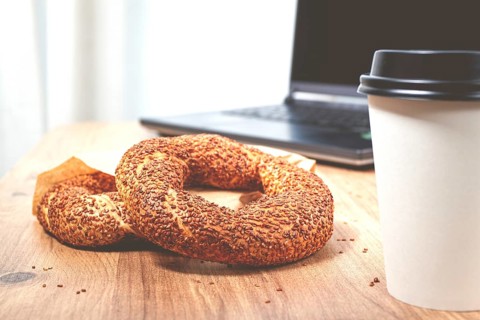 Simits with coffee on a wooden table, with a laptop, in a cozy working environment, snack,