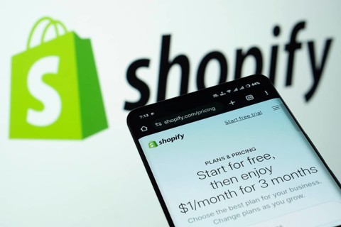 Dhaka, Bangladesh- 03 July 2025: Smartphone displaying Shopify web interface against Shopify logo