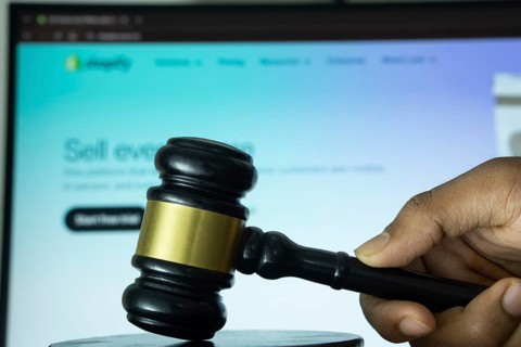 Dhaka, Bangladesh- 20 June 2025: A hand holds a gavel in front of a computer screen displaying