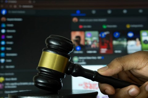 Dhaka, Bangladesh- 20 June 2025: A hand holds a gavel in front of a computer screen displaying